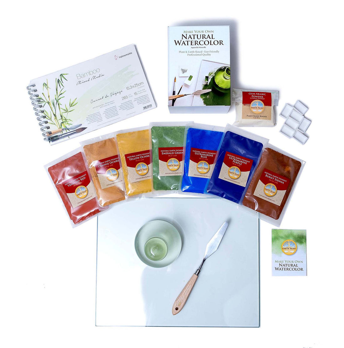 Components of the Deluxe Natural Watercolor Mixing Set including glass palette, glass muller, palette knife, spiral-bound bamboo watercolor paper and the Natural Watercolor Kit including seven pigment packets, gum arabic, seven watercolor pans and instruction booklet