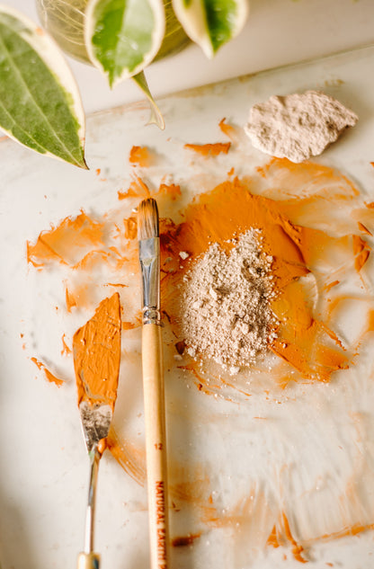 mixing orange oil paint on pallet with pallet knife and brush