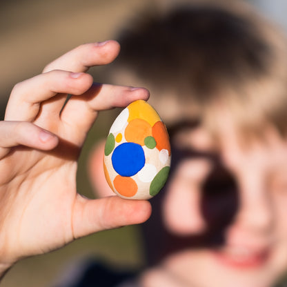 childs hand holding painted wooden egg